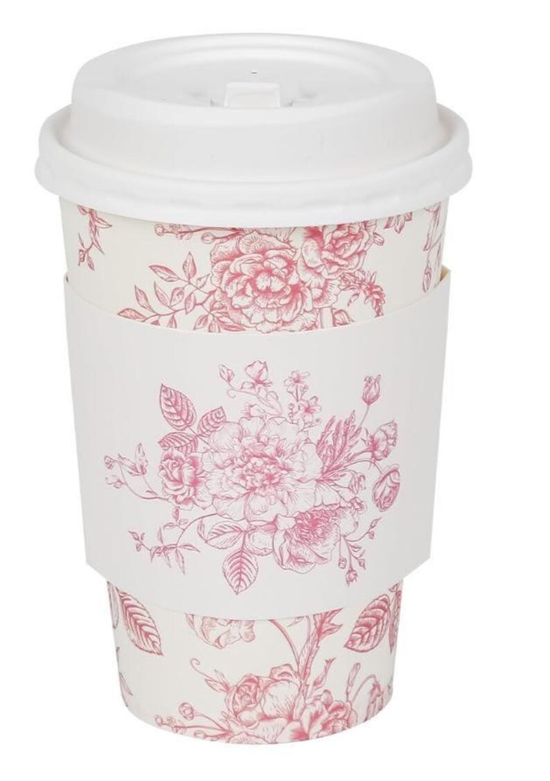 May include: A white disposable coffee cup with a matching lid and a pink floral design. The cup has a white sleeve with the same floral pattern. The floral design includes roses and other flowers.