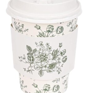 May include: A white disposable coffee cup with a matching lid. The cup has a floral design in green and white, with a matching white sleeve. The floral pattern includes roses and other flowers.