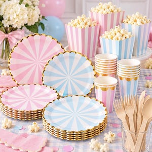 Puede incluir: Un juego de artículos para fiestas con platos de papel a rayas rosas y azules con bordes dorados festoneados, vasos de papel a juego, cajas de palomitas llenas y cubiertos de madera sobre una superficie a cuadros.