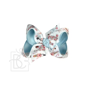 May include: A hair bow made of light blue grosgrain ribbon featuring a repeating pattern of nutcrackers, ballerinas, and candy canes. The center of the bow is gathered with a matching light blue ribbon knot, creating a structured, multi-looped design.