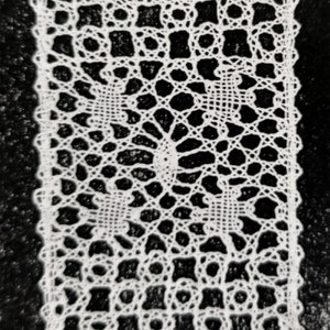 May include: White crocheted lace doily with a delicate floral pattern. The lace is intricate and detailed, with a circular design in the center.