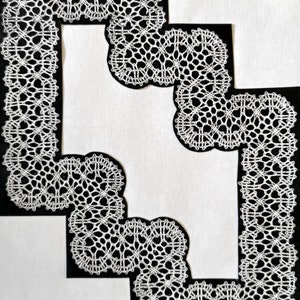 May include: White lace trim with a geometric pattern, framed by black paper.