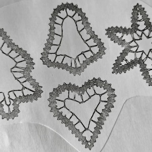 Może przedstawiać: Trzy czarne koronki w kształcie serca, gwiazdy i choinki.