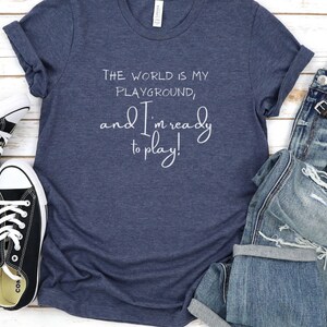 Op de afbeelding: Een marineblauw T-shirt met de tekst "The world is my playground, and I'm ready to play!" in wit.