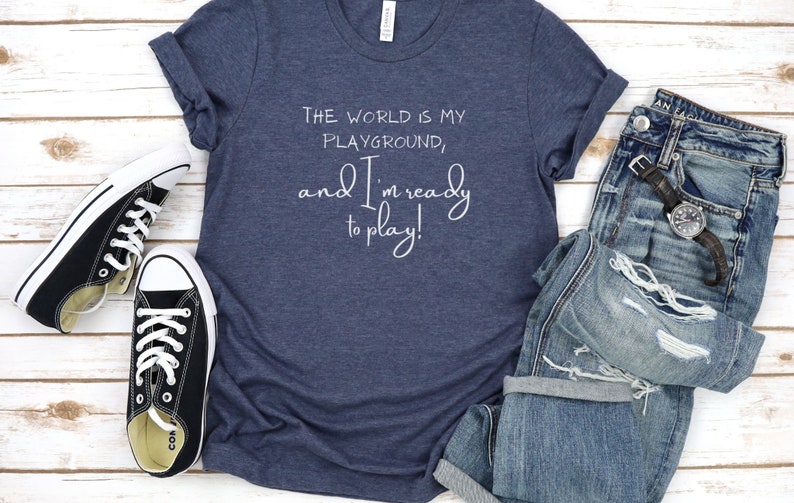 Op de afbeelding: Een marineblauw T-shirt met de tekst "The world is my playground, and I'm ready to play!" in wit.