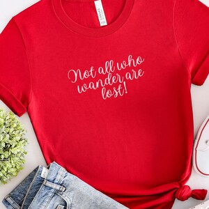 May include: Red short-sleeved t-shirt with the text "Not all who wander are lost!" in white lettering.