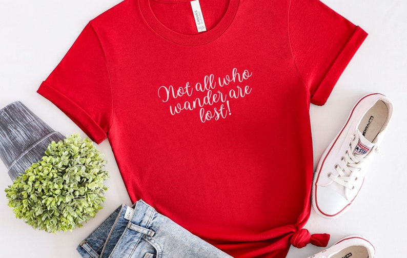 May include: Red short-sleeved t-shirt with the text "Not all who wander are lost!" in white lettering.