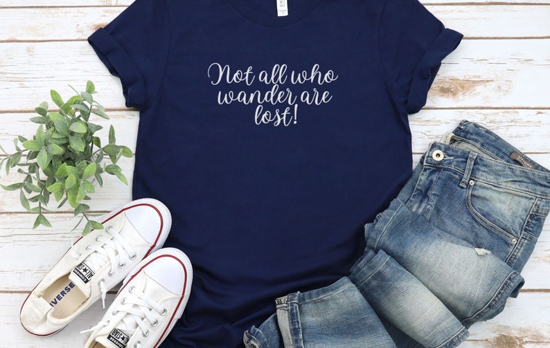 May include: A navy blue t-shirt with the text "Not all who wander are lost!" in white lettering.