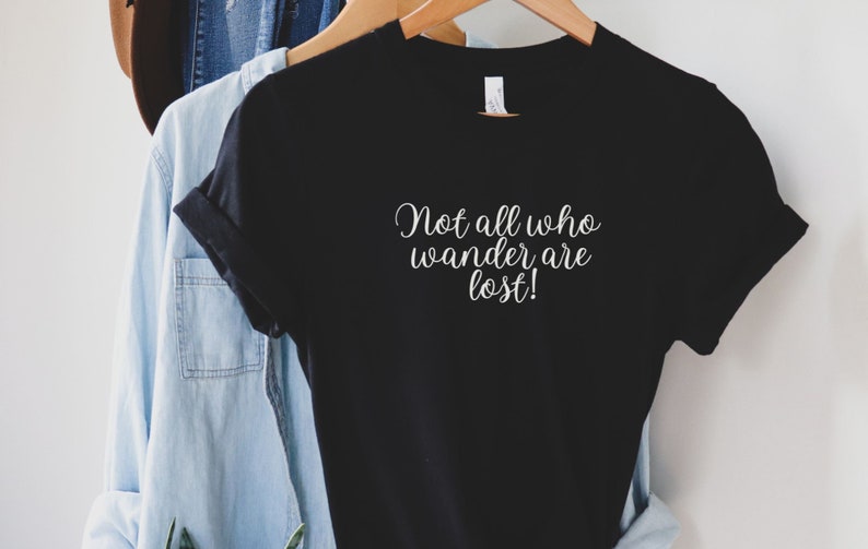 May include: Black t-shirt with white text that reads "Not all who wander are lost!"
