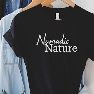 May include: Black t-shirt with white text that reads "Nomadic Nature" on a black t-shirt.