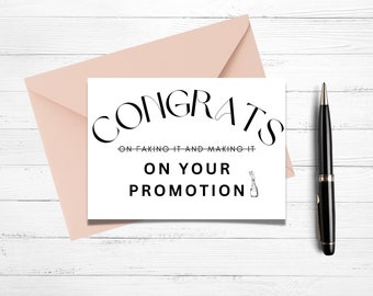 May include: A white card with black text that reads "Congrats on faking it and making it on your promotion". A champagne bottle graphic is next to the text. The card is sitting on a light wood surface with a pink envelope and a black pen.