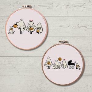 Puede incluir: Dos aros de bordado con tela blanca y diseños de punto de cruz de familias de fantasmas haciendo truco o trato para Halloween. El primer aro muestra una familia de cuatro fantasmas con un gato. El segundo aro muestra una familia de cinco fantasmas con un bebé en un cochecito y un gato.