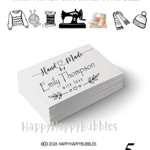 May include: A stack of white rectangular organic cotton labels featuring the black printed text Hand Made by Emily Thompson with love and decorative heart and leaf icons. Above the labels are black line art icons of sewing supplies.