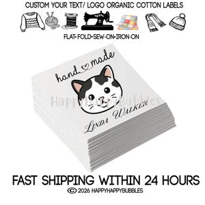 May include: A stack of white square organic cotton labels featuring the text hand made with a heart symbol, a black and white cat face illustration, and the name LINDA WALKER printed in black. The top of the image shows icons of clothing.