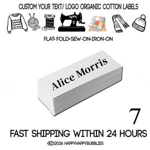 以下が含まれることがあります： Alice Morrisと黒い文字が印刷された白い長方形のオーガニックコットンラベルの束。束の上には、セーター、毛糸、糸巻き、ミシン、キルト、スカーフ、帽子の黒いアイコンがあります。テキスト：CUSTOM YOUR TEXT/LOGO ORGANIC COTTON LABELS。