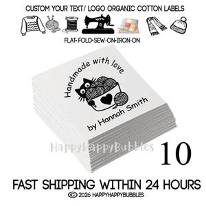 May include: A stack of white square organic cotton labels featuring a black graphic of a cat holding a ball of yarn, with the text Handmade with love by Hannah Smith. The top label displays the cat illustration and custom text clearly.