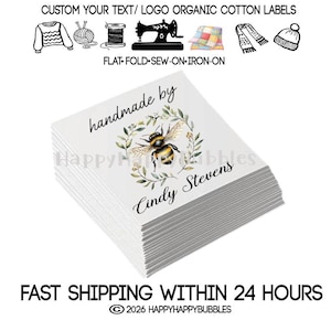 May include: A stack of white square organic cotton labels featuring a printed design of a bumblebee inside a green leafy wreath. The text reads handmade by Cindy Stevens. Above the stack are icons of a sweater, yarn, spool, sewing machine, quilt, scarf, and hat.