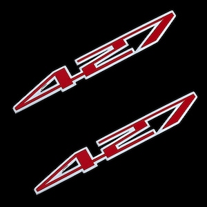 May include: Two red and white stylized automotive decals with a sharp, angular design. The decals feature a red "42" design with white outlines, set against a black background. The design is sleek and modern.