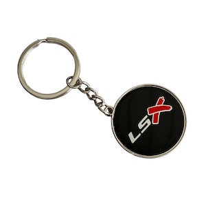 May include: A silver keychain with a black round charm. The charm has a white "LS" with a red "X" on a black background.