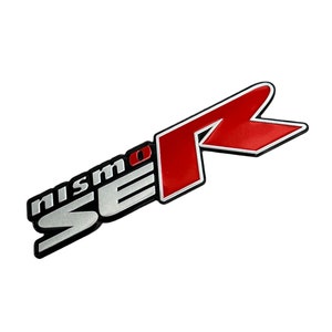 May include: Silver and red NISMO emblem with the letters "NISMO" and "R" in a stylized font.