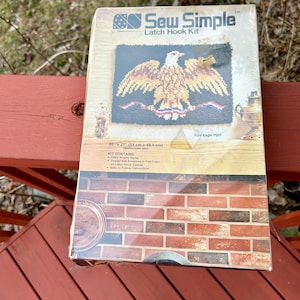 May include: A latch hook kit featuring a bold eagle design with red, white, and blue accents. The kit includes 100% acrylic yarn, a design silk screen in full color on a latch hook canvas, and easy-to-follow instructions. The finished project measures 20 inches by 27 inches.