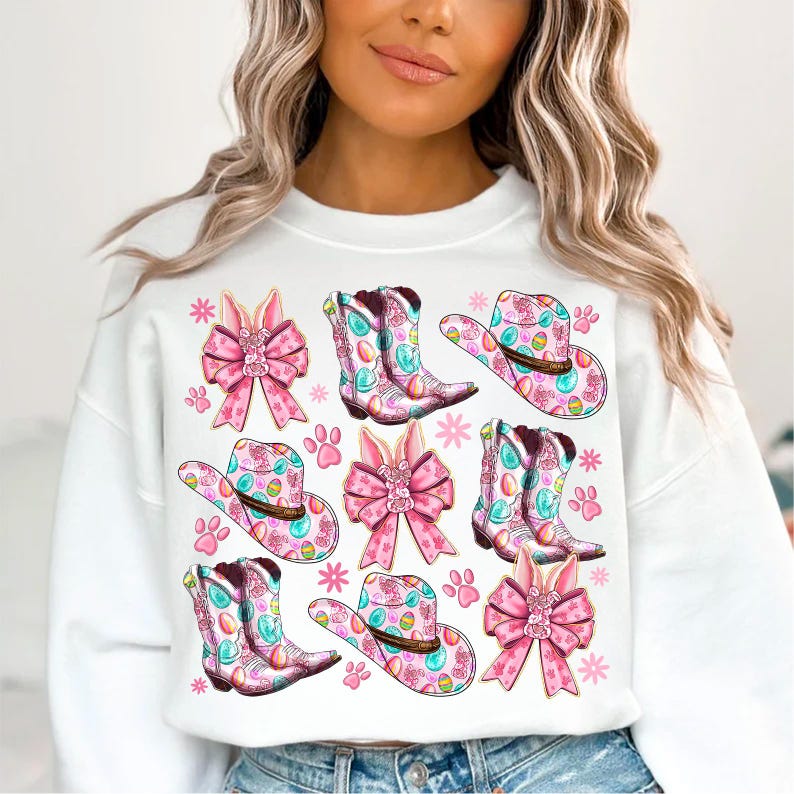 Peut inclure: Sweat-shirt blanc avec un motif de P&acirc;ques rose et bleu. Le motif repr&eacute;sente des bottes de cow-boy, des chapeaux, des n&oelig;uds et des oreilles de lapin.