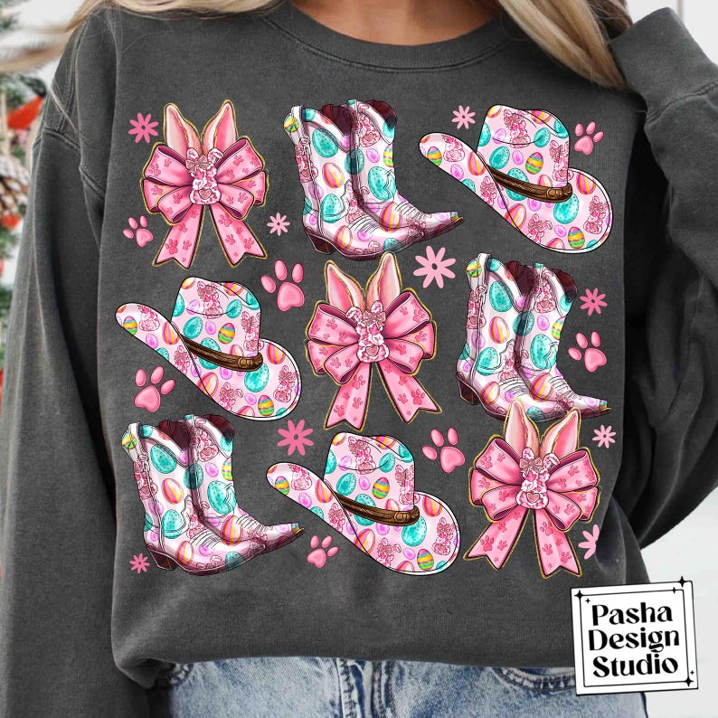 Peut inclure: Un sweat-shirt gris avec un motif de P&acirc;ques color&eacute;. Le motif pr&eacute;sente des n&oelig;uds roses, des bottes de cow-boy et des chapeaux de cow-boy avec des &oelig;ufs de P&acirc;ques. Le texte "Pasha Design Studio" est dans le coin inf&eacute;rieur droit.