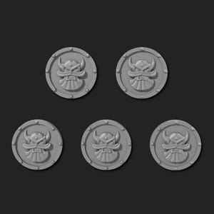 May include: Five grey, circular tokens featuring a raised, stylised skull design. Each token has a border with small, evenly spaced rivets. The skull has horns and a detailed face, suggesting a fantasy or gaming theme.