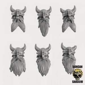 May include: Six grey miniature Viking helmet and beard figurines. Each figurine features a horned helmet, a long beard, and detailed facial features. The figurines are arranged in two rows of three, with a logo in the bottom right corner.