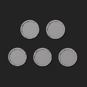 May include: Six round, gray metal shields with a raised rim and small, evenly spaced studs around the edge.