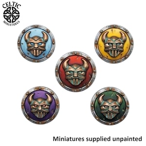 May include: Five circular shields featuring a central bronze-colored horned helmet relief. The shields are painted in light blue, yellow, red, purple, and green, each with a metallic silver rim. Text includes Celtic Miniatures and Miniatures supplied unpainted.