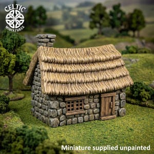 Op de afbeelding: Een miniatuur stenen huisje met een getextureerd rieten dak, een opvallende schoorsteen, een kleine houten deur en een raam met meerdere ruiten. De structuur is in grijze en beige tinten, met de tekst Celtic Miniatures zichtbaar.