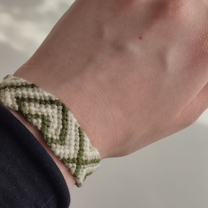 Puede incluir: Un brazalete de amistad verde y blanco con un patrón de chevron.