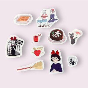 May include: A set of nine stickers featuring characters and objects from the animated film Kiki's Delivery Service. The stickers include Kiki, Jiji the black cat, a cake with the word "KIKI" on it, a broom, a red phone, a heart with an arrow, a cage with Jiji inside, a couple sitting on a bench, and a black cat with a red flower.