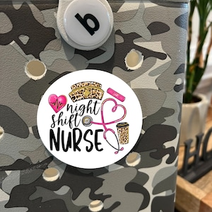May include: A white round sticker with a pink heart, a stethoscope, a coffee cup, and a leopard print nurse's hat. The text on the sticker reads "night shift NURSE".