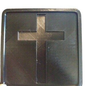 Pu&ograve; includere: Un quadrato di plastica nera con un ritaglio a forma di croce al centro. La croce &egrave; leggermente rialzata rispetto alla superficie del quadrato.