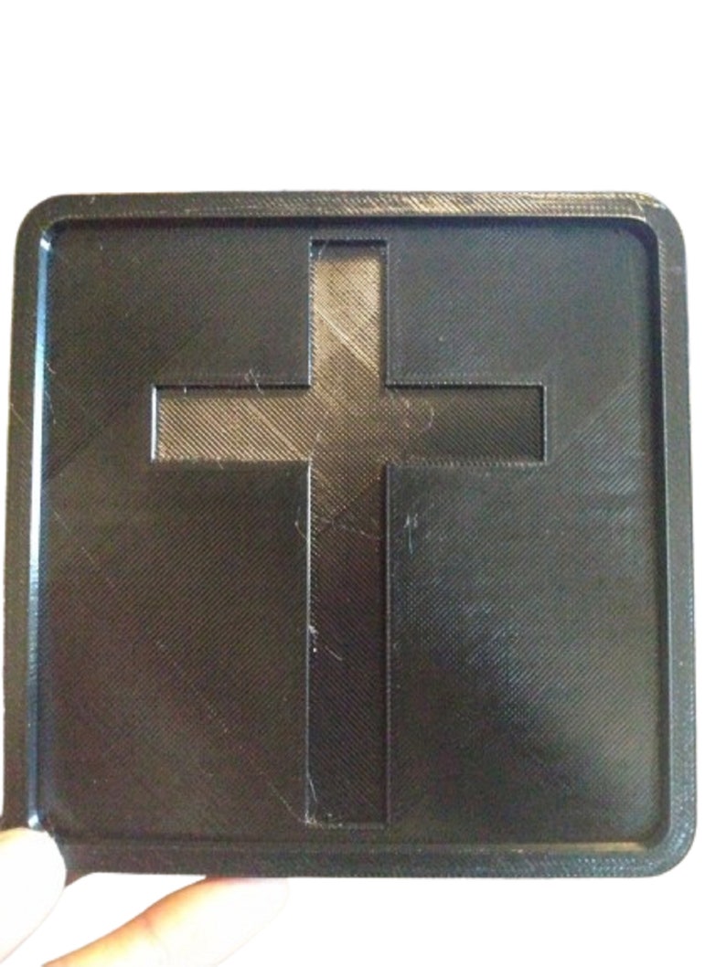 Pu&ograve; includere: Un quadrato di plastica nera con un ritaglio a forma di croce al centro. La croce &egrave; leggermente rialzata rispetto alla superficie del quadrato.