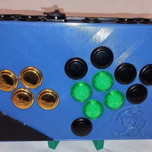 May include: A blue and black arcade controller with gold and green buttons. The controller has a logo that says "Lost Worlds".