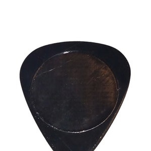 Pu&ograve; includere: Un plettro per chitarra nero con un bordo arrotondato e una superficie liscia.