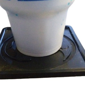 Pu&ograve; includere: Un sottobicchiere quadrato nero con un design rialzato. Il sottobicchiere &egrave; realizzato in un materiale simile alla gomma e ha una superficie liscia. Una tazza in ceramica bianca &egrave; appoggiata sul sottobicchiere.