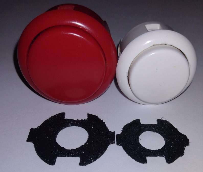 Puede incluir: Dos botones redondos de arcade, uno rojo y otro blanco, con anillos de pl&aacute;stico negro alrededor del bot&oacute;n. Dos anillos de pl&aacute;stico negro con un agujero en el centro.