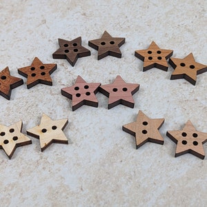 May include: A collection of 10 wooden star-shaped buttons in various shades of brown, pink, and natural wood. Each button has five points and four holes.
