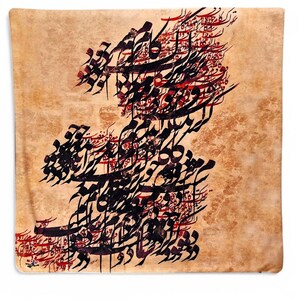 May include: A square, tan-colored decorative pillow featuring intricate black and red calligraphy. The calligraphy is arranged in a flowing, artistic design across the pillow's surface. The pillow has a soft, textured appearance.