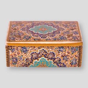 May include: A small wooden box with a decorative floral design. The box is painted in shades of gold, blue, green, and white. The design features intricate paisley patterns and floral motifs.