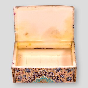 May include: A small, decorative box with a hinged lid. The box is made of wood and is painted with a colorful floral pattern. The inside of the box is lined with a soft, white material.