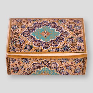 May include: A small wooden box with a decorative design. The box is painted with a gold background and intricate patterns in blue, green, and white. The lid of the box is closed.