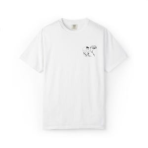 May include: White t-shirt with a small black and white illustration of two people embracing. The shirt has a crew neck and short sleeves. The illustration is located on the upper left chest area of the shirt.