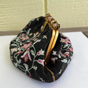 May include: A black beaded evening bag with a floral design and a gold clasp.