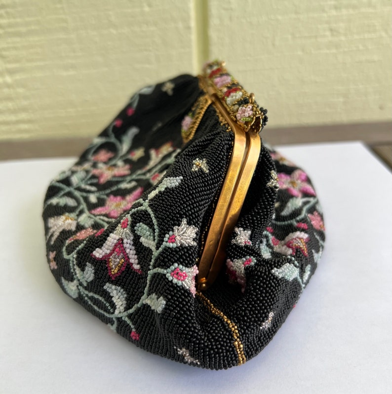 May include: A black beaded evening bag with a floral design and a gold clasp.