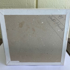 May include: A white cardboard box with a brown interior. The box has a handwritten inscription that reads "99 puzzle blocks".